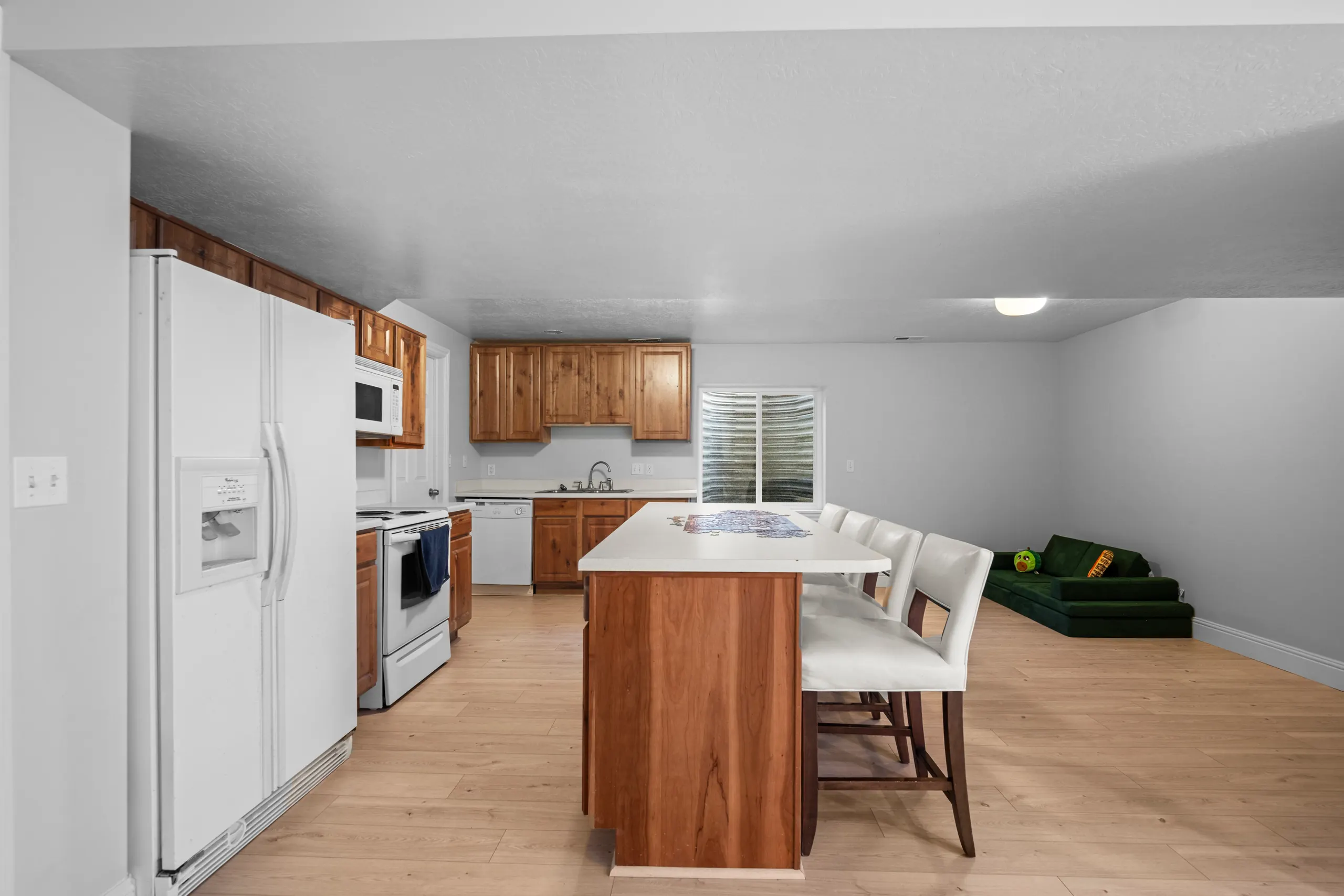 Basement kitchenette with a full-size range, dishwasher and refrigerator, knotty alder cabinetry and an island with bar stools