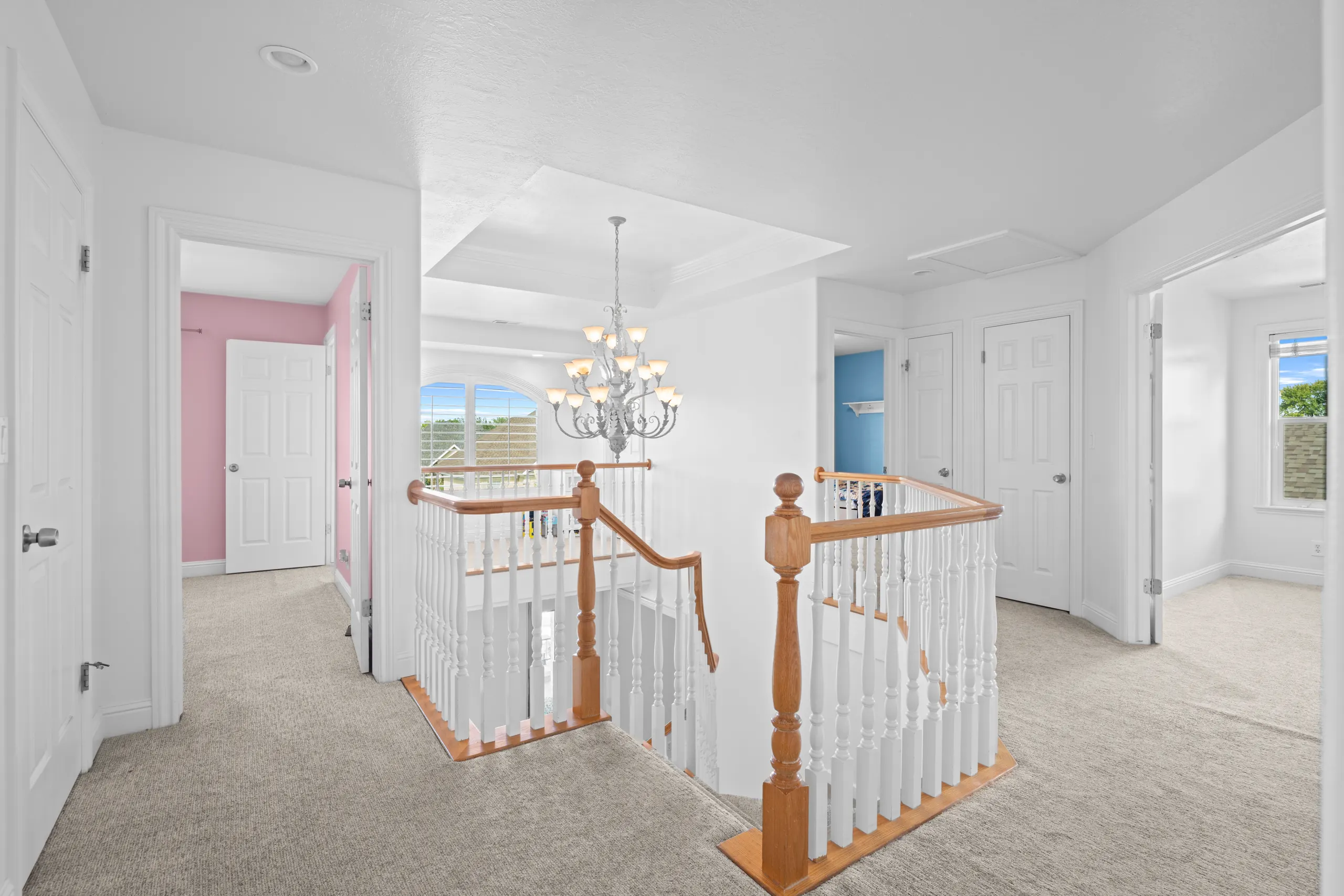 Upstairs landing with an oak-railed open balcony over the stairwell, a chandelier and doorways to the bedrooms