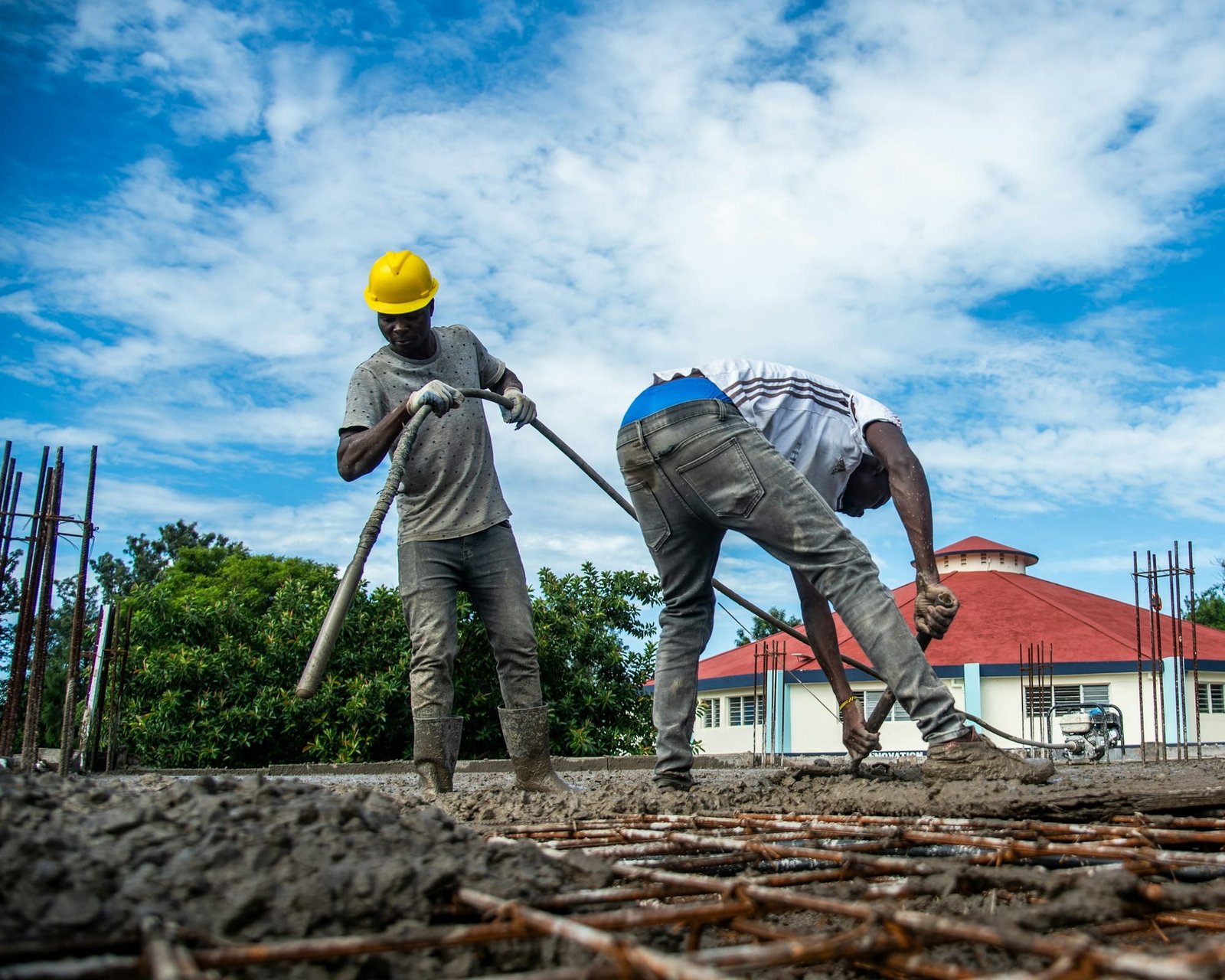 Construction crew in hard hats spreading fresh concrete on a sunny day