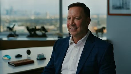 Executive in a navy blazer being interviewed in his office